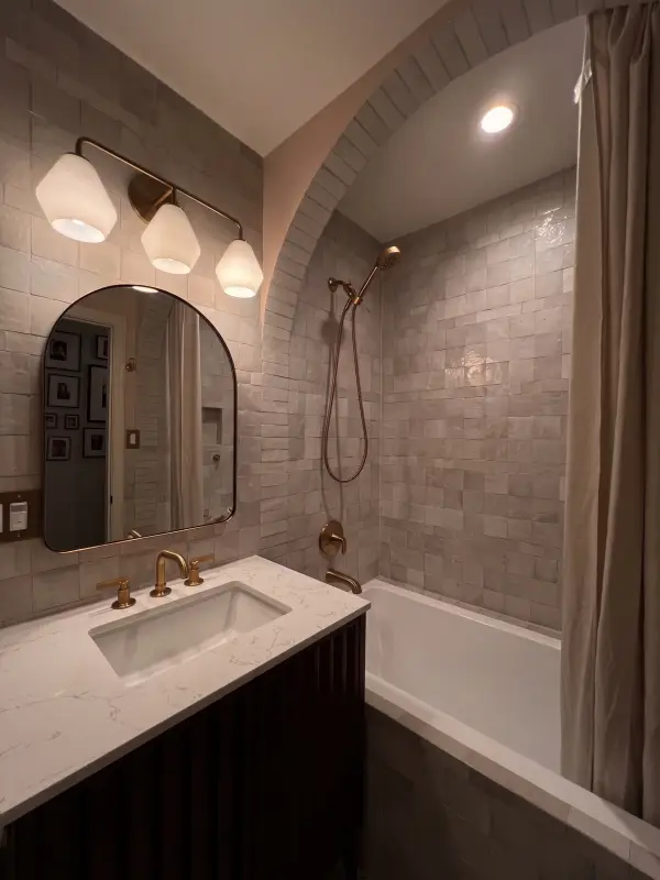 Handmade glazed tile bath with an arched tub alcove and brass fixtures