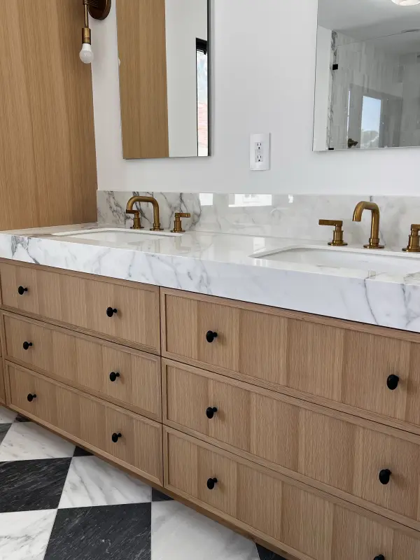 Light oak double vanity with a marble-look top and brass faucets